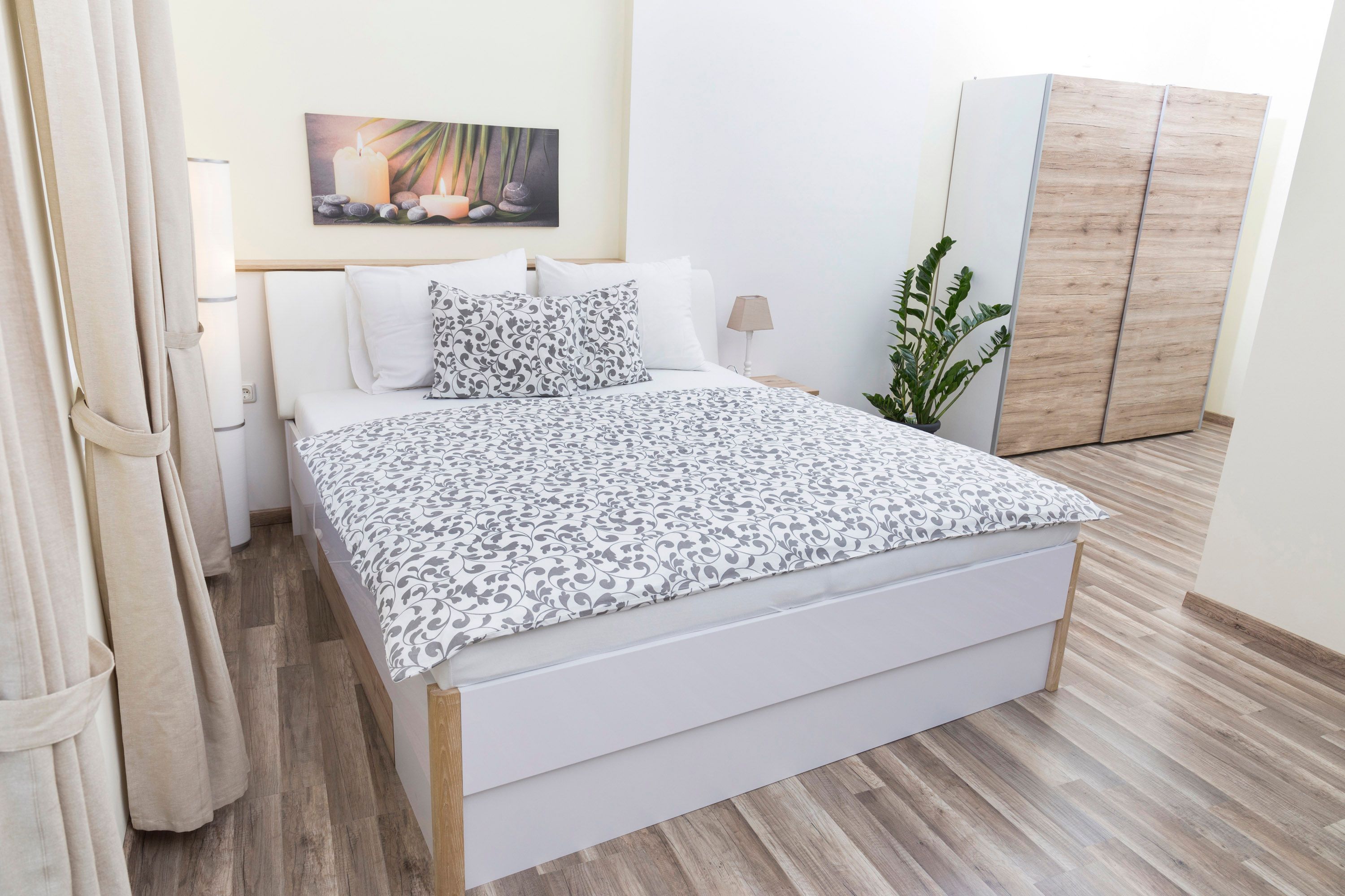 Moderná spálňa s manželskou posteľou, rastlinami a šatníkovou skriňou.