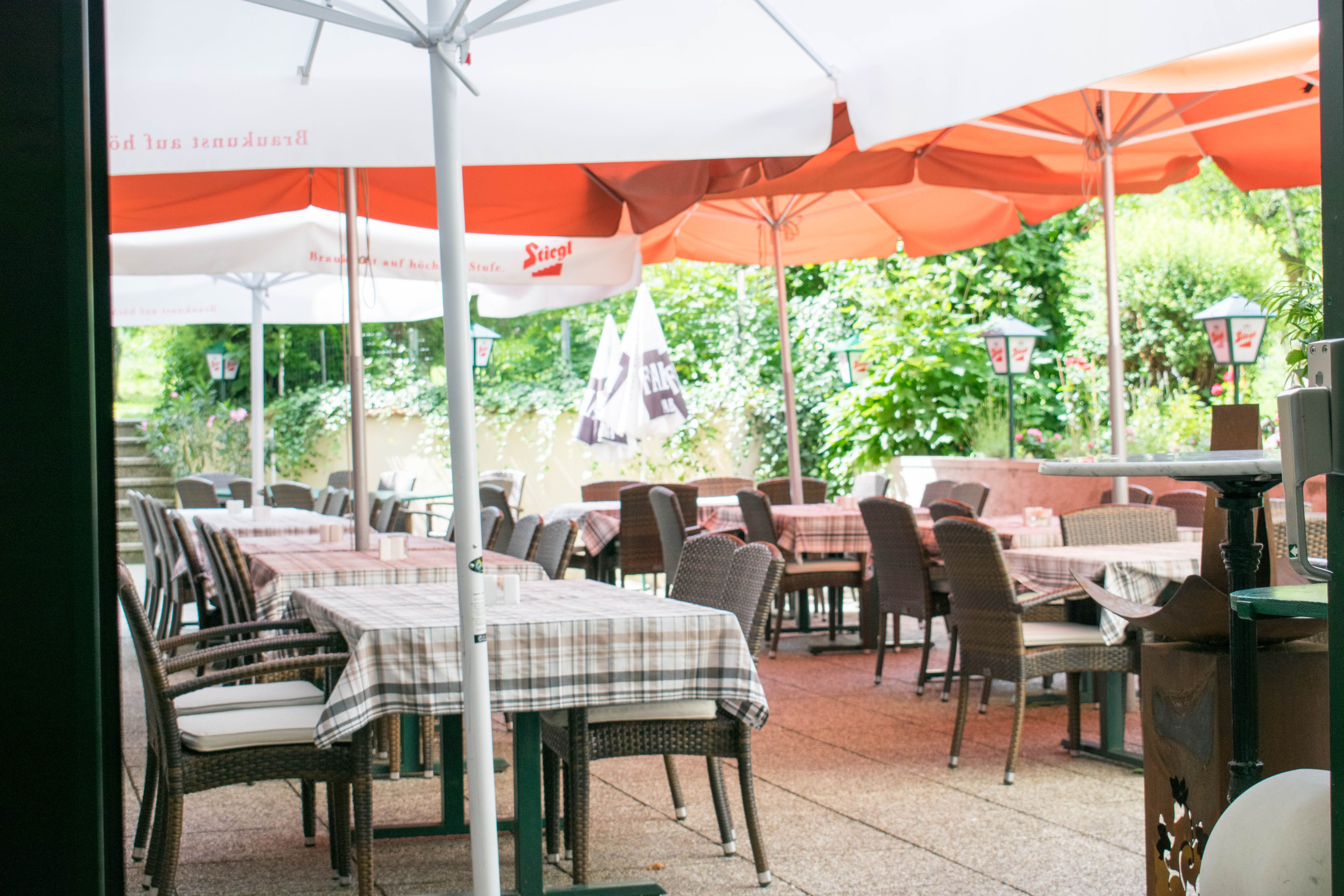 Vonkajší priestor kaviarne so stolmi, stoličkami a slnečníkmi.