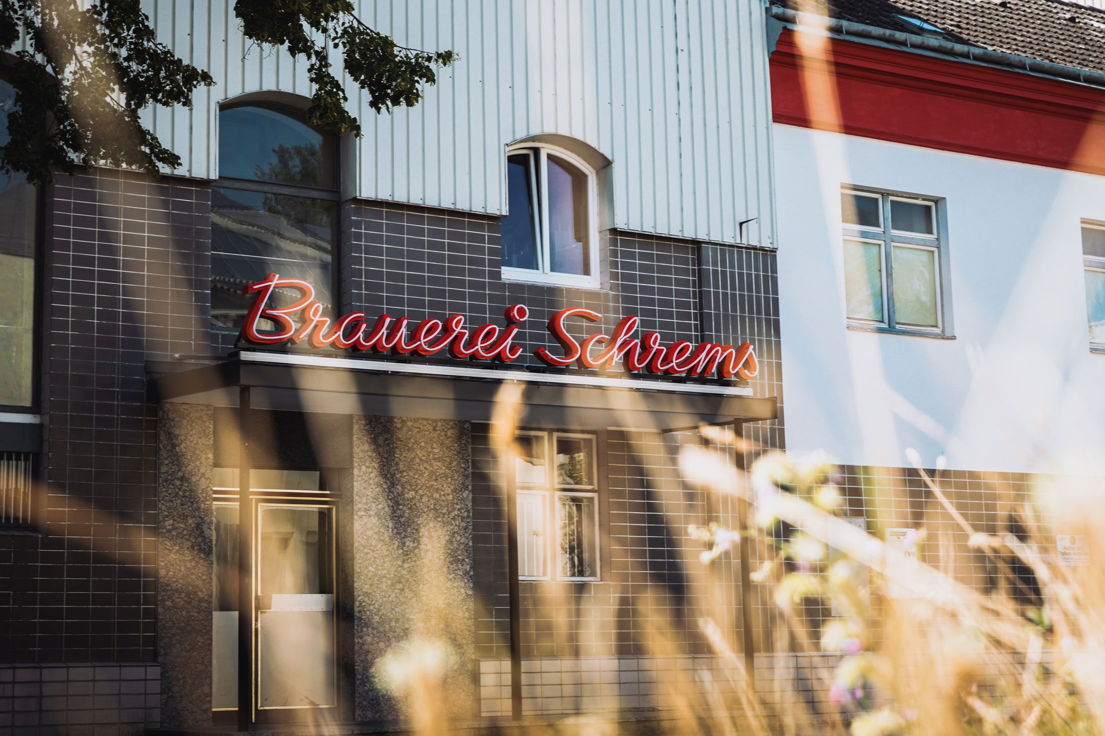 Fasáda pivovaru Schrems s červeným osvetleným nápisom.