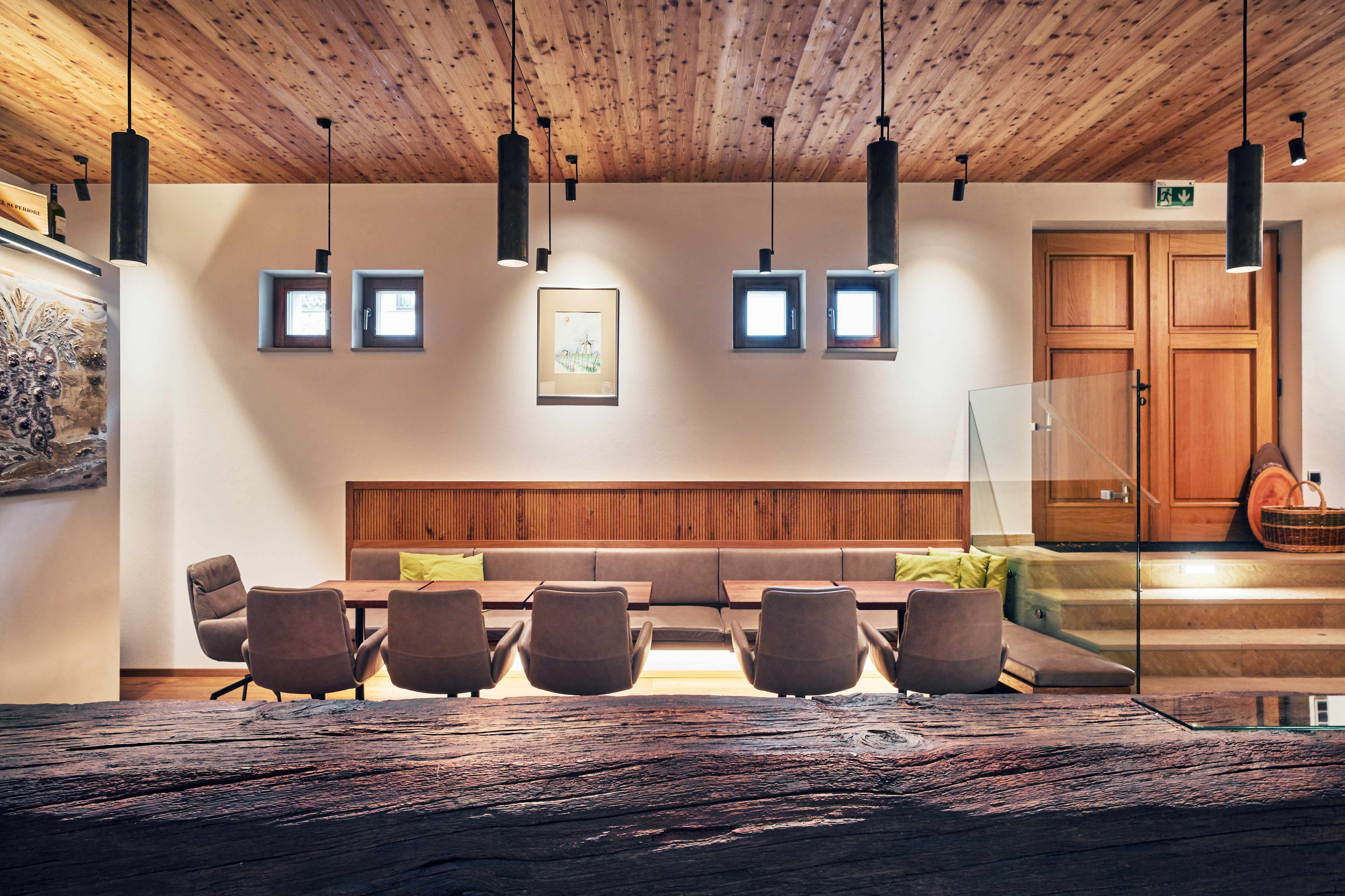 Moderný interiér s drevenými prvkami, posedením a dekoratívnymi lampami.