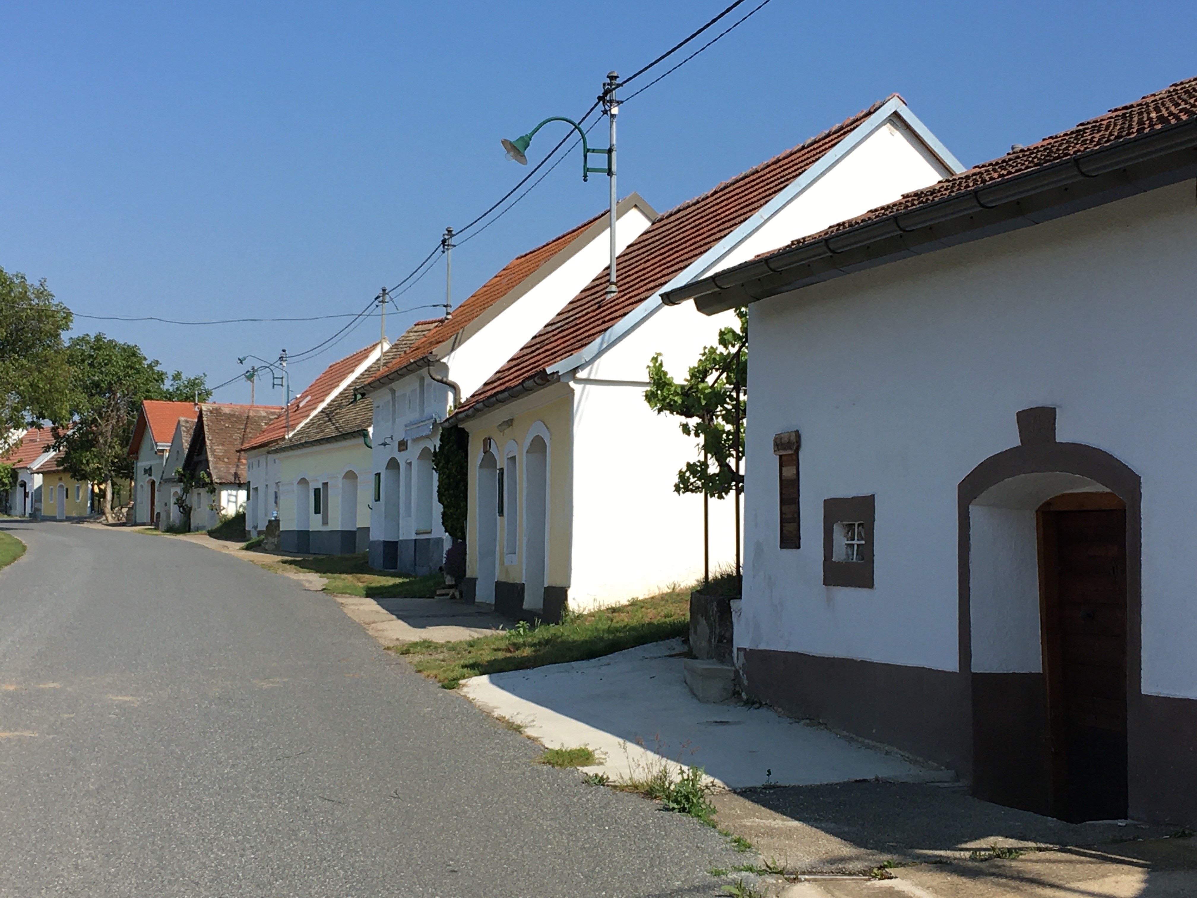 Tichá ulica s tradičnými obielenými domami a červenými strechami vo vidieckom prostredí.