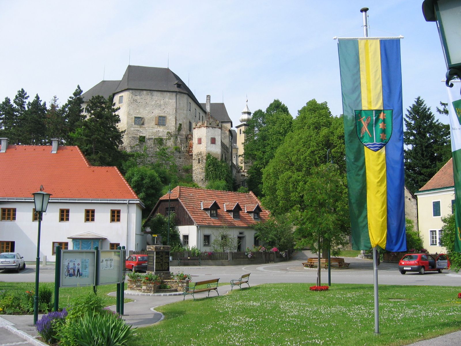 Hlavné námestie v Albrechtsbergu s hradom v pozadí a vlajkou v popredí.