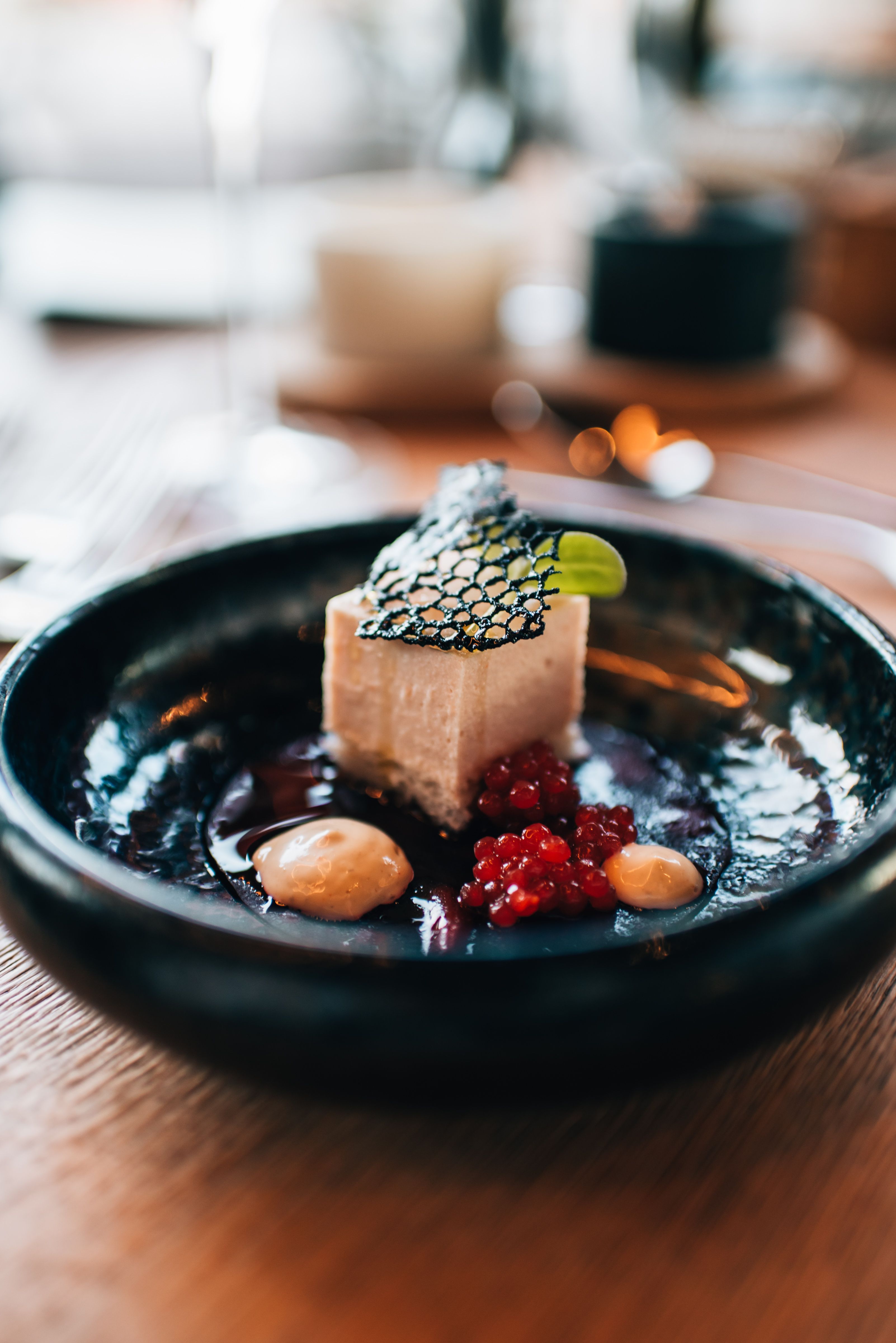 Moderná vinárska architektúra za súmraku s osvetlenými interiérmi a okolitými budovami.