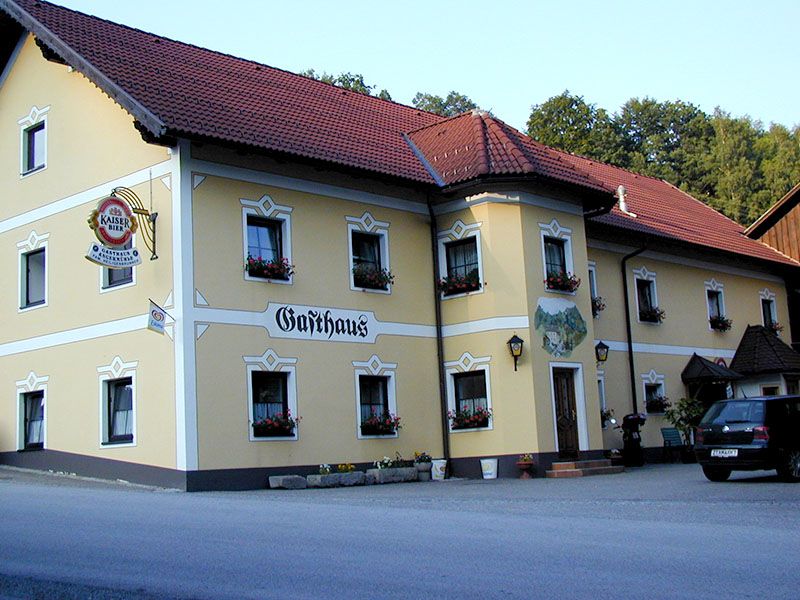 Tradičný hostinec so žltou fasádou a červenými škridlami na streche.