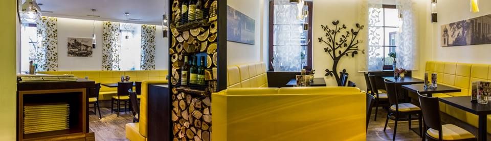 Pohľad do interiéru reštaurácie so žltými lavicami a dekoratívnymi prvkami.