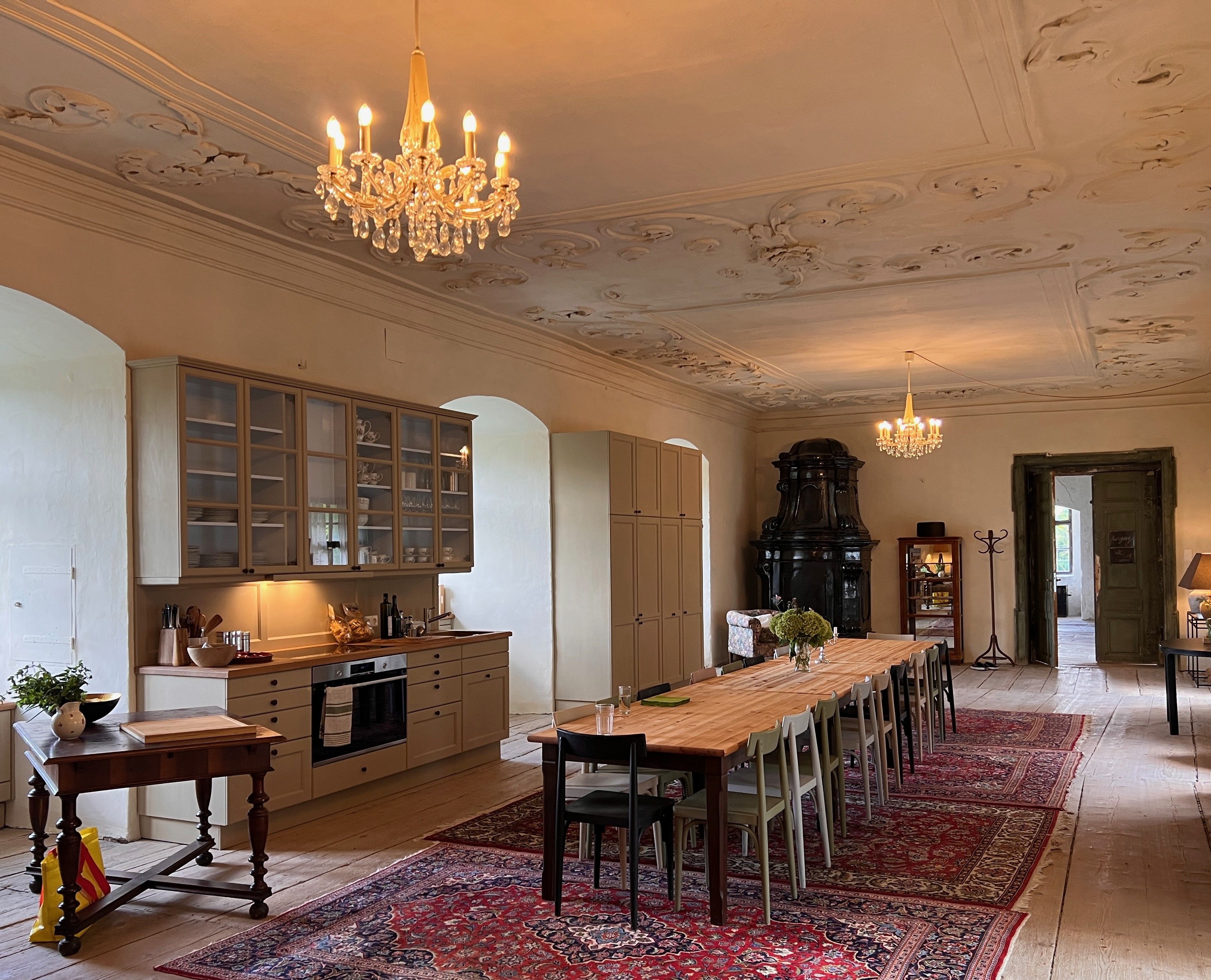 Elegantná jedáleň s dlhým dreveným stolom, lustrami a starožitnou pecou.