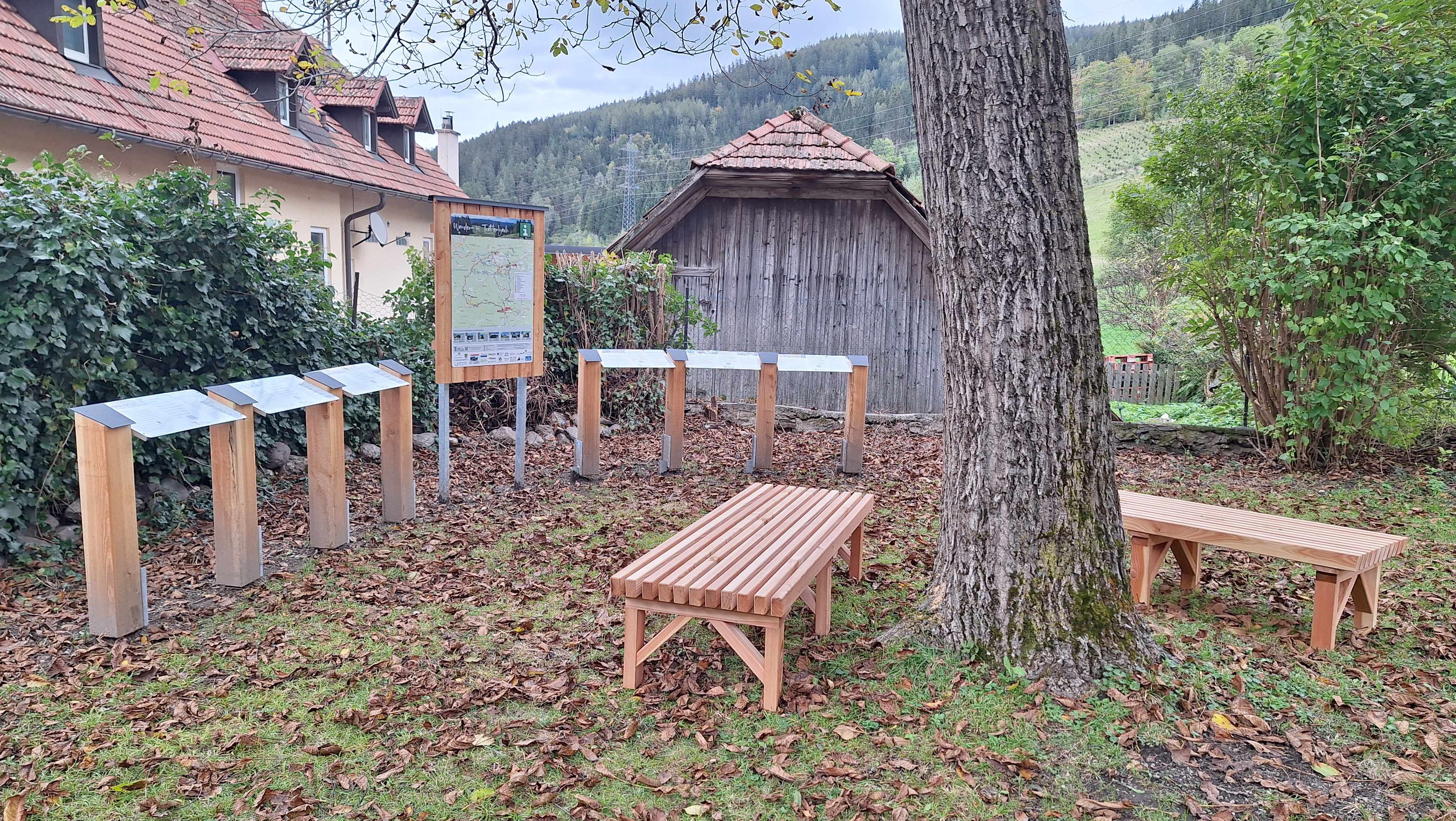 Drevené lavičky a informačné tabule v záhrade Wittgensteinhausu.