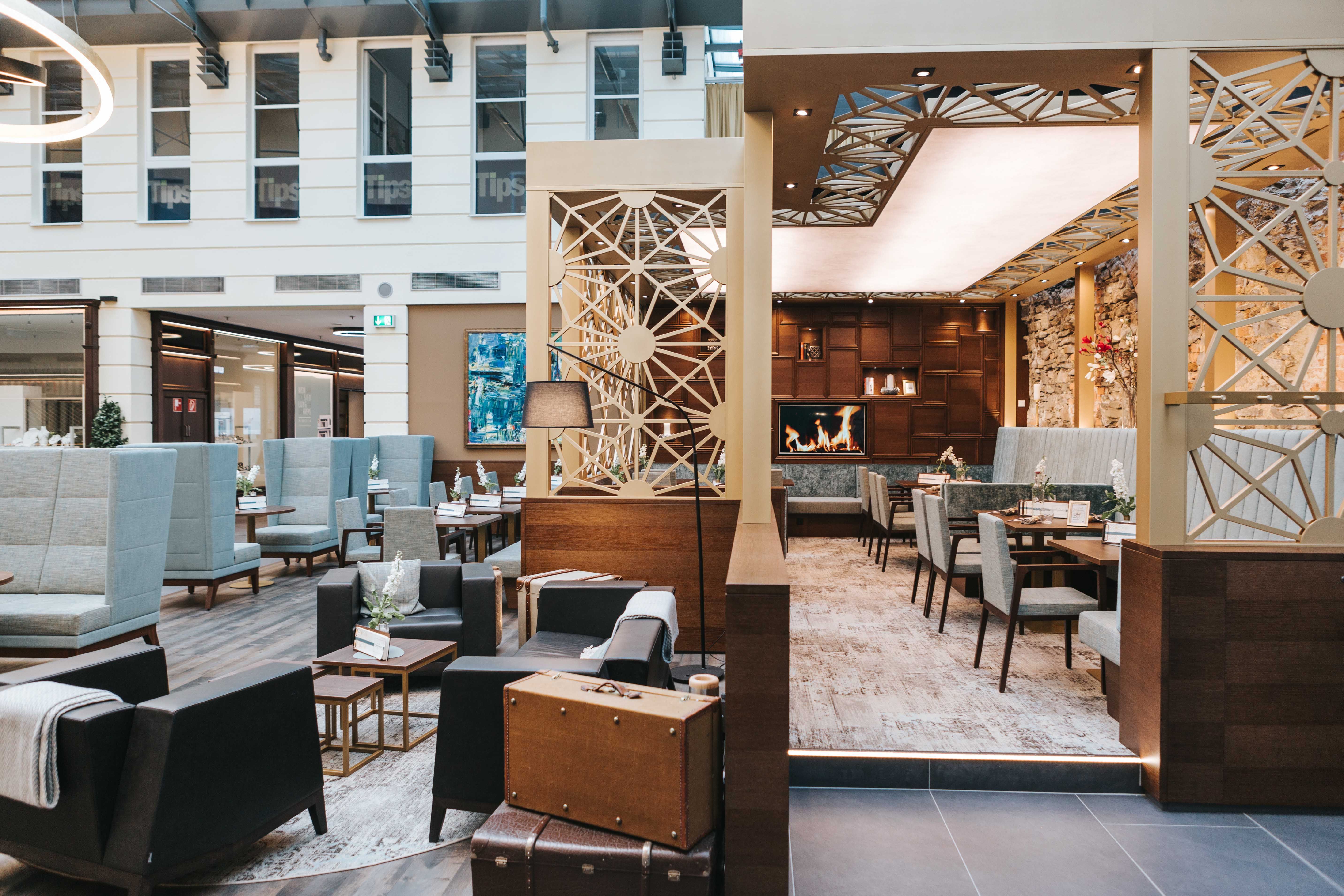 Pohľad do interiéru modernej kaviarne s útulným posedením, krbom a štýlovou výzdobou.