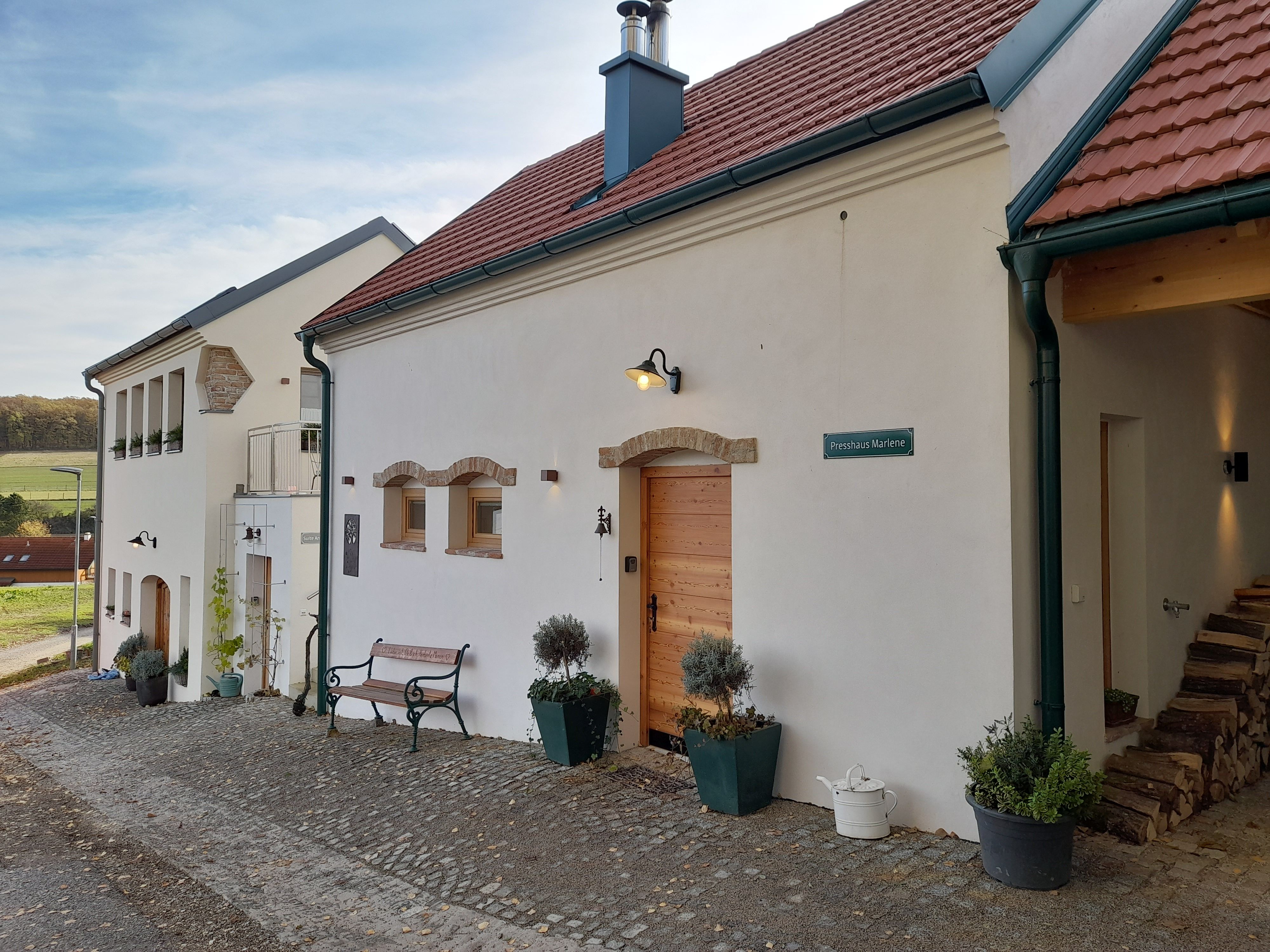 Zrekonštruovaná budova s červenou škridlovou strechou a bielou fasádou na ekologickej farme.