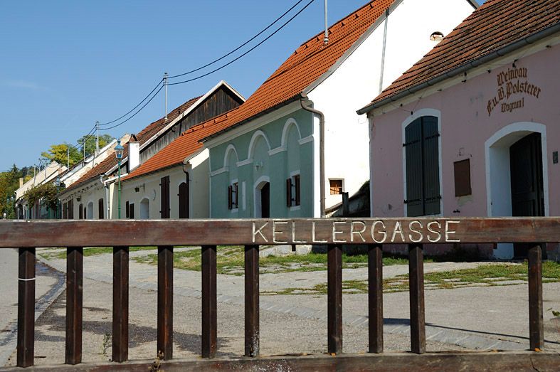 Historická vínna ulička v Grafenwörthu s farebnými budovami a dreveným plotom v popredí.