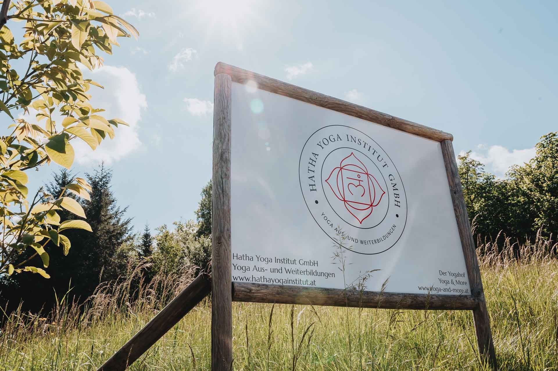 Na lúke pod slnečnou oblohou stojí nápis Hatha Yoga Institute.