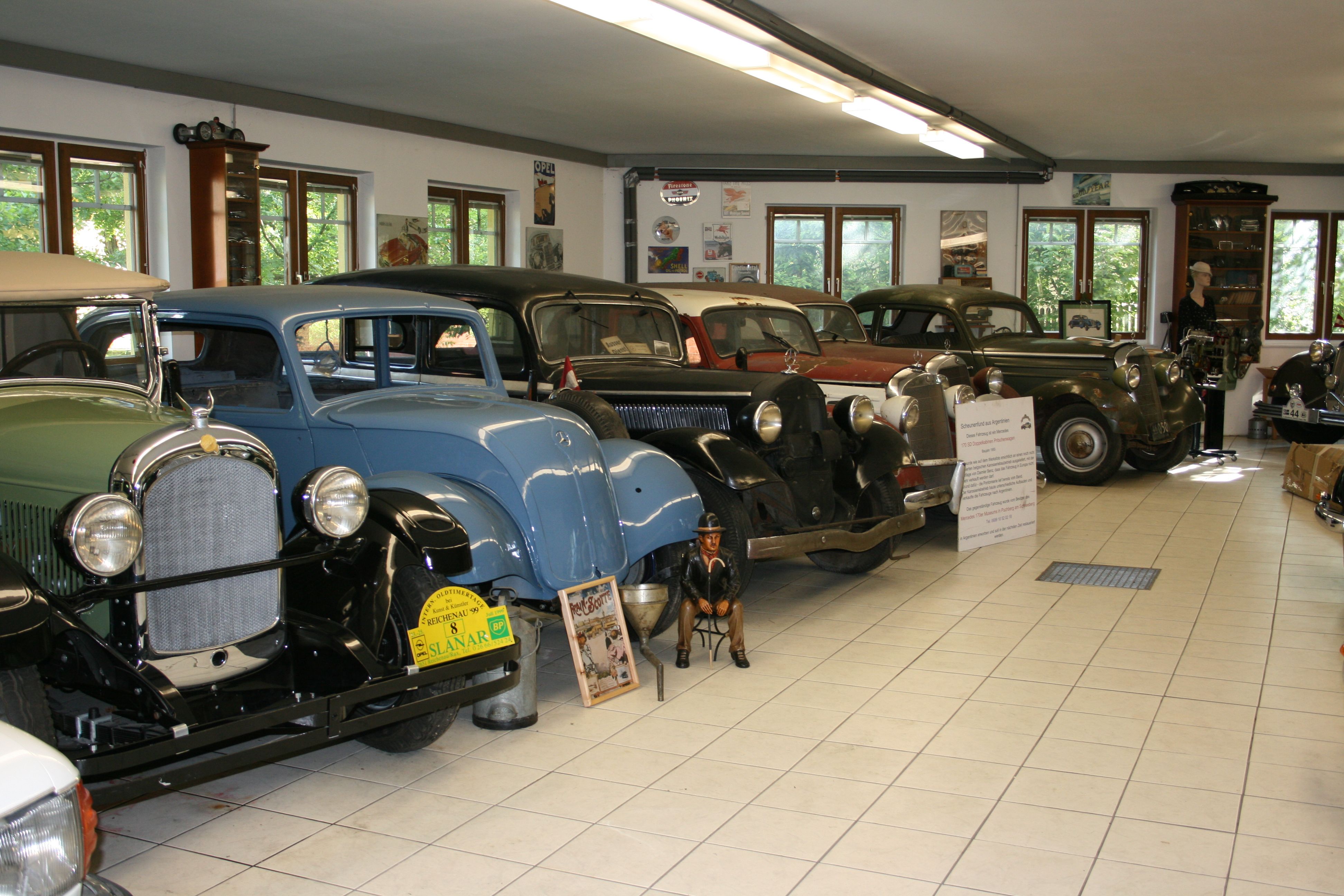 Pohľad do interiéru múzea klasických automobilov s niekoľkými klasickými automobilmi v rade za sebou.