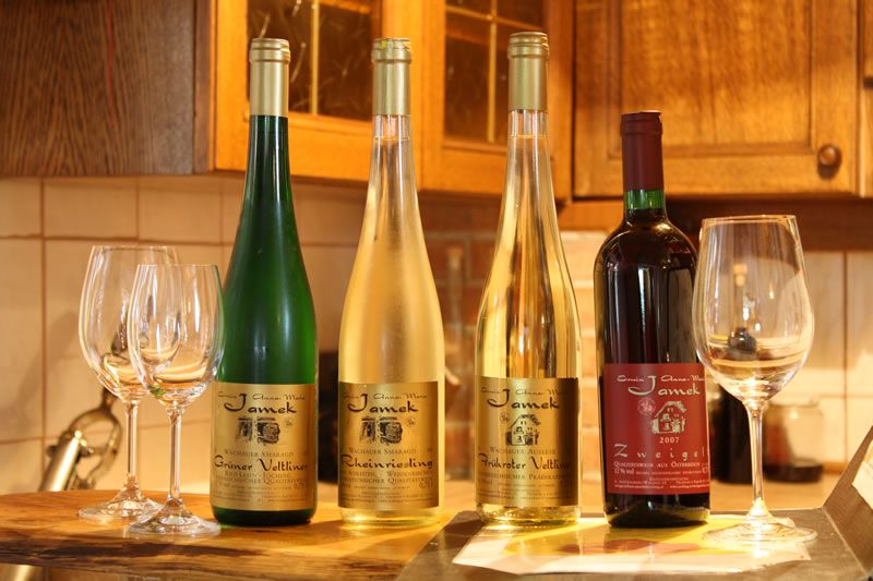 Štyri fľaše vína a poháre na stole v kuchyni.