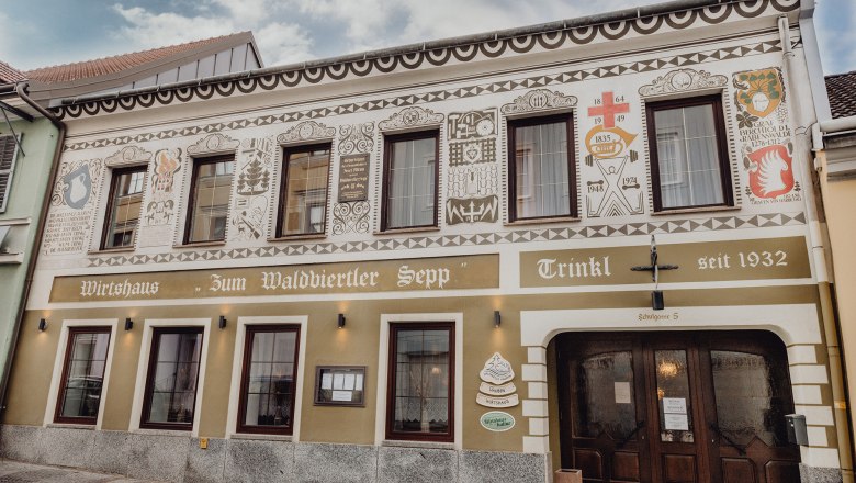 Fasáda tradičného hostinca s dekoratívnymi maľbami a nápisom "Zum Waldviertler Sepp" v obci Schrems.