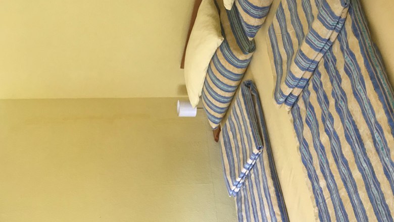 Sp&aacute;lňa s manželskou posteľou, pruhovan&aacute; posteľn&aacute; bielizeň, žlt&eacute; steny, mal&yacute; obr&aacute;zok na stene.