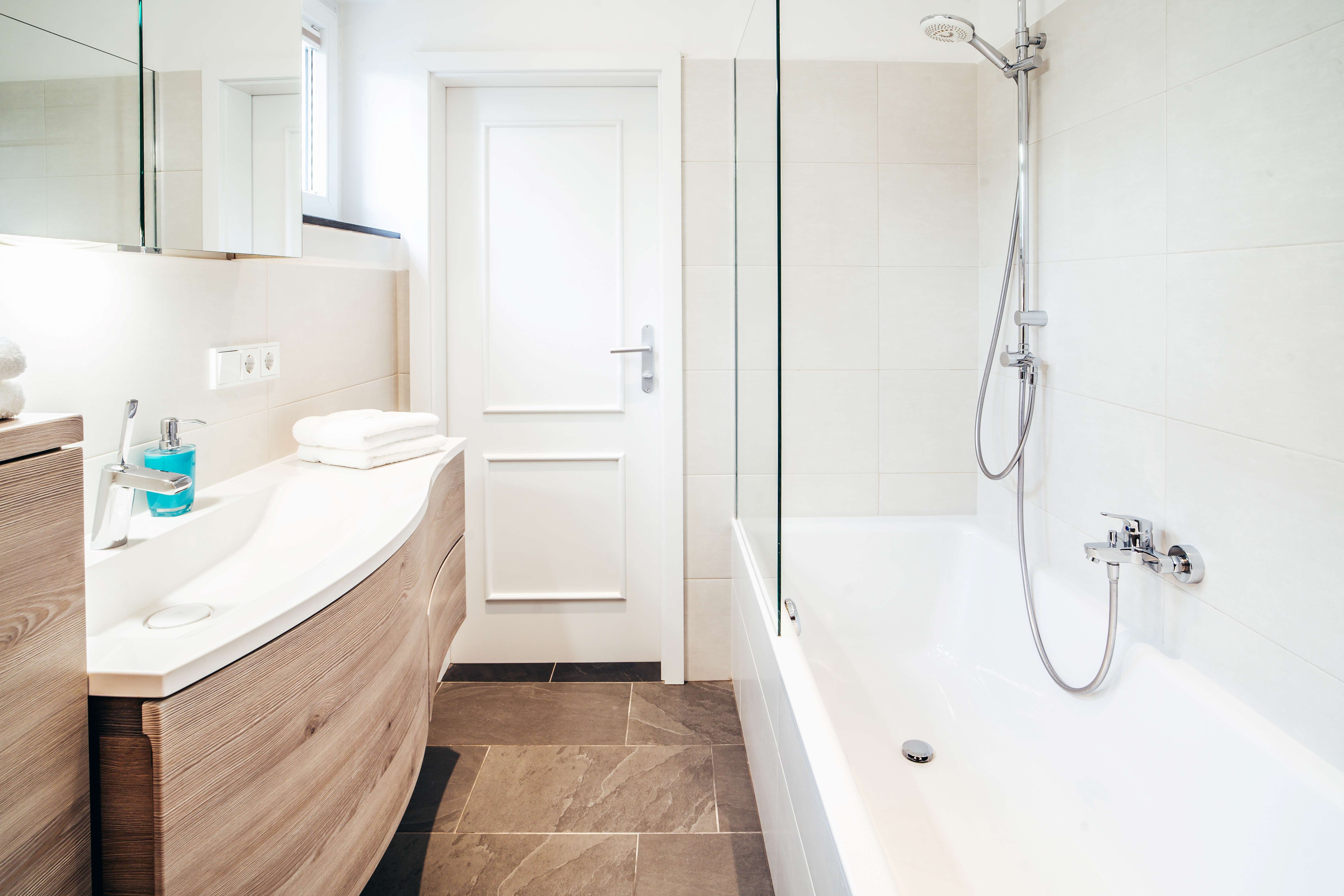 Moderná kúpeľňa s vaňou, umývadlom a zrkadlom.