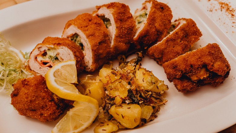 Plnen&eacute; pečen&eacute; morčacie fil&eacute; so zemiakovou pr&iacute;lohou a pl&aacute;tkami citr&oacute;na na bielom tanieri.