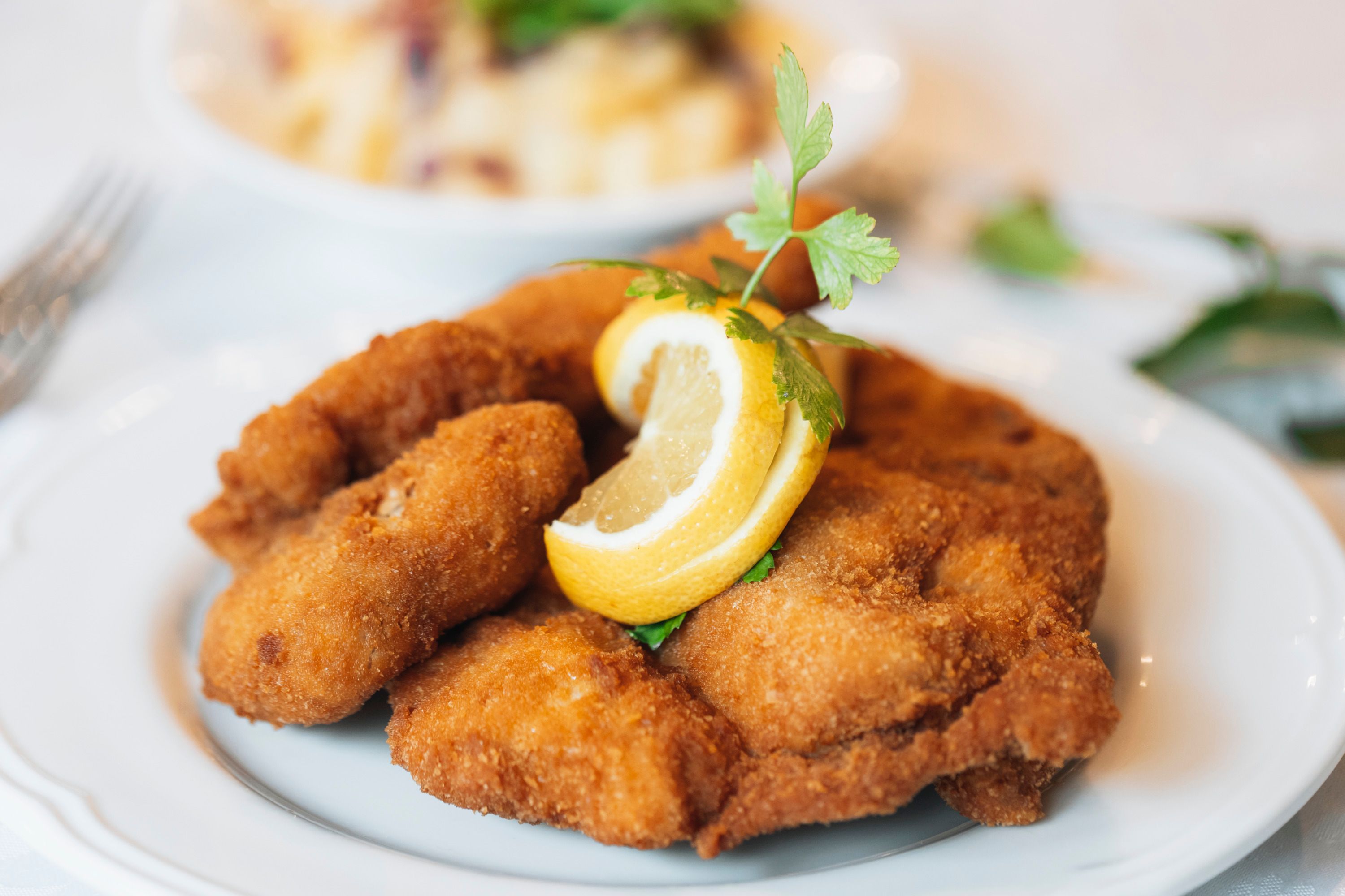 Pečené kurča s plátkom citróna a petržlenovou vňaťou na tanieri.