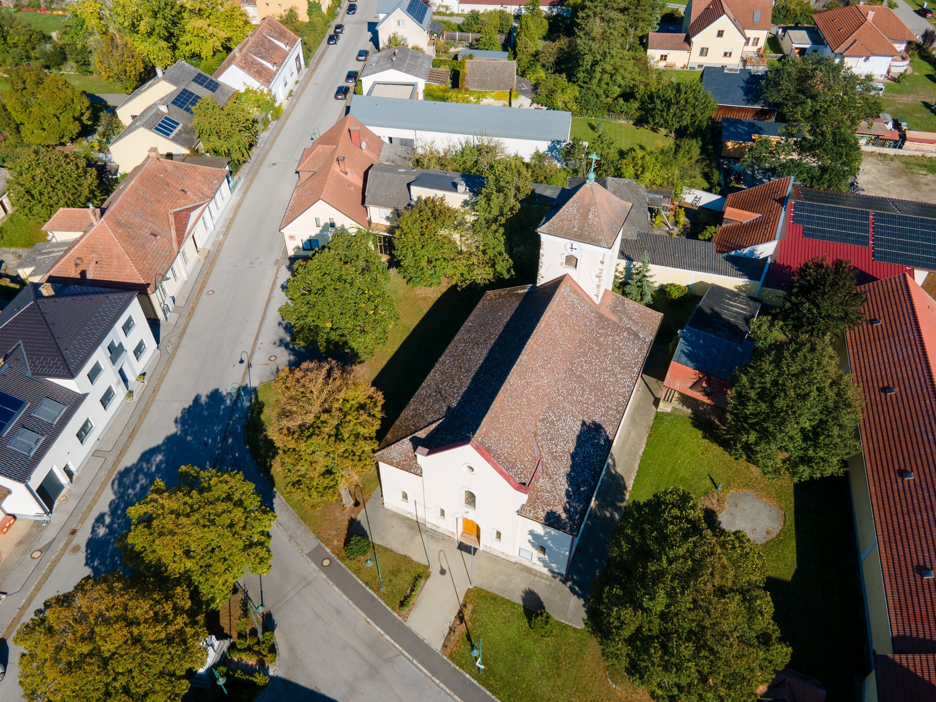 Letecký pohľad na obec Weiden an der March s kostolom, obytnými domami, ulicami a množstvom zelene.
