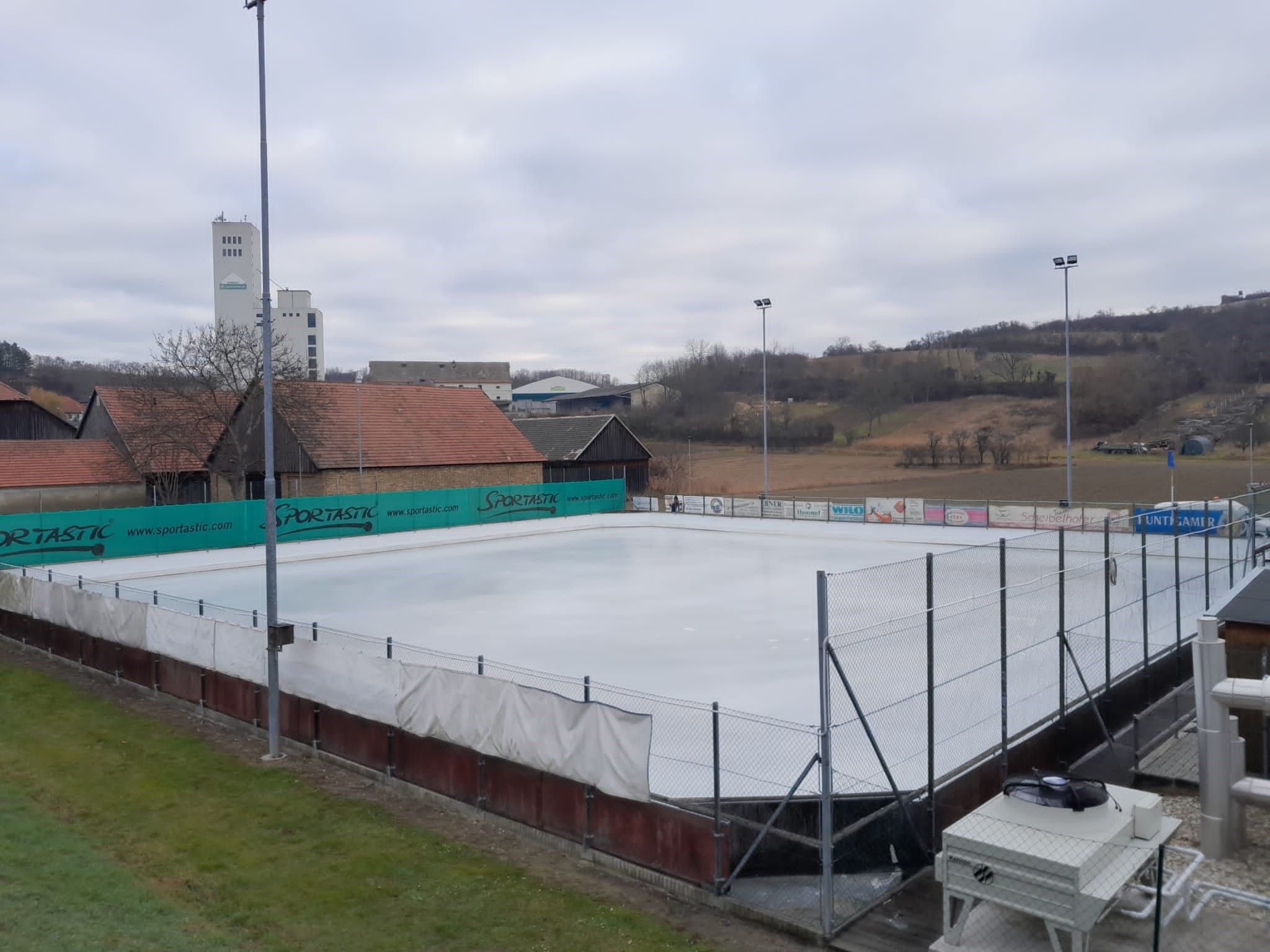 Prázdne klzisko s okolitými budovami a kopcami v pozadí.