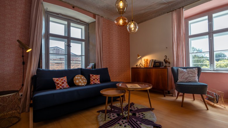 &Uacute;tuln&aacute; ob&yacute;vacia izba s pohovkou, kreslami, kobercom a z&aacute;vesn&yacute;mi lampami.