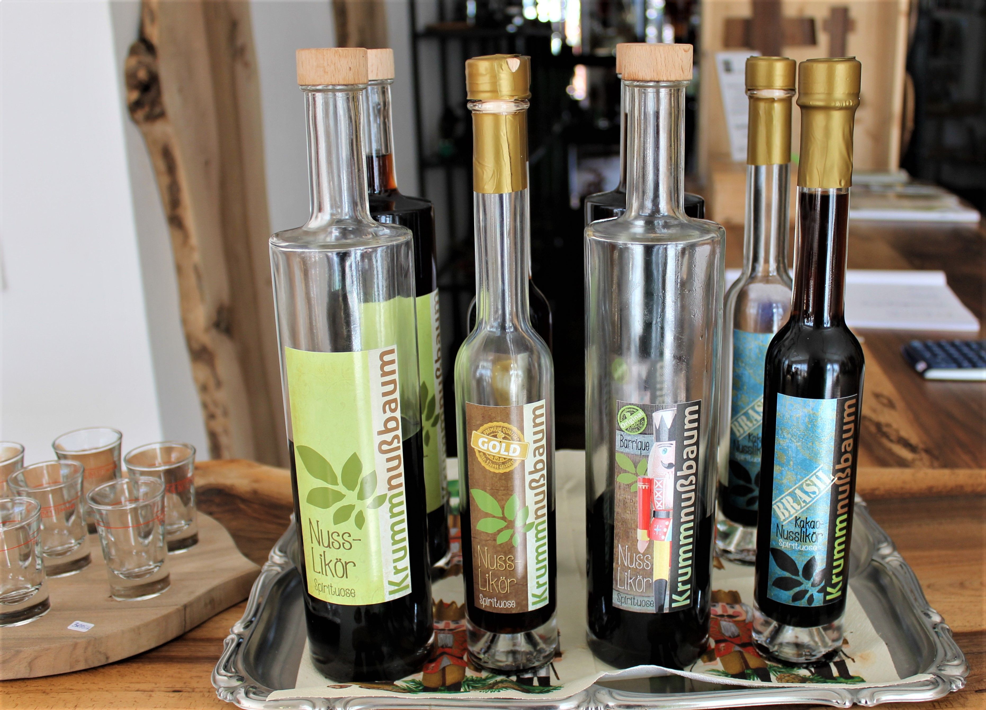 Niekoľko fliaš orechového likéru na podnose a poháre vedľa nich.