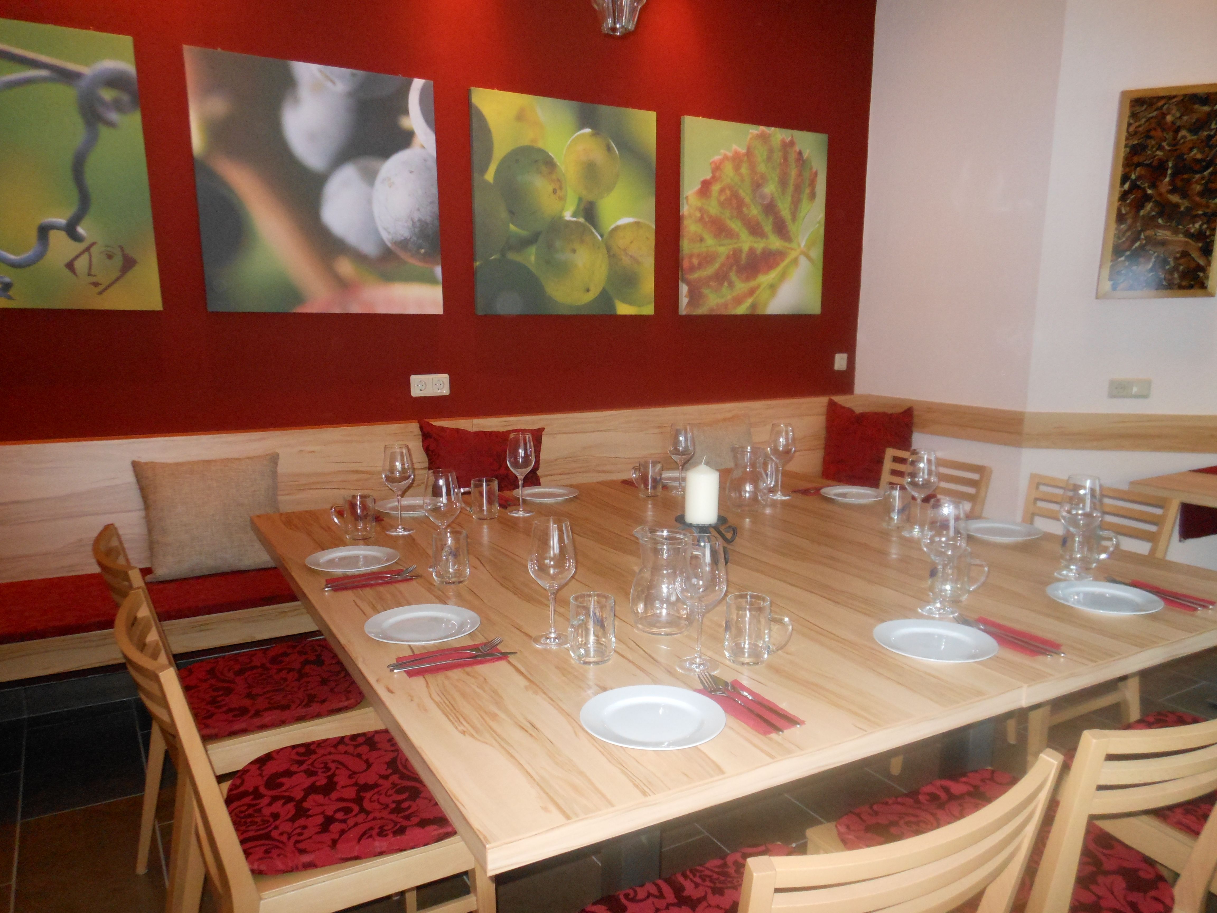 Degustačná miestnosť so zastrešeným dreveným stolom, pohármi na víno a nástennými maľbami hrozna.