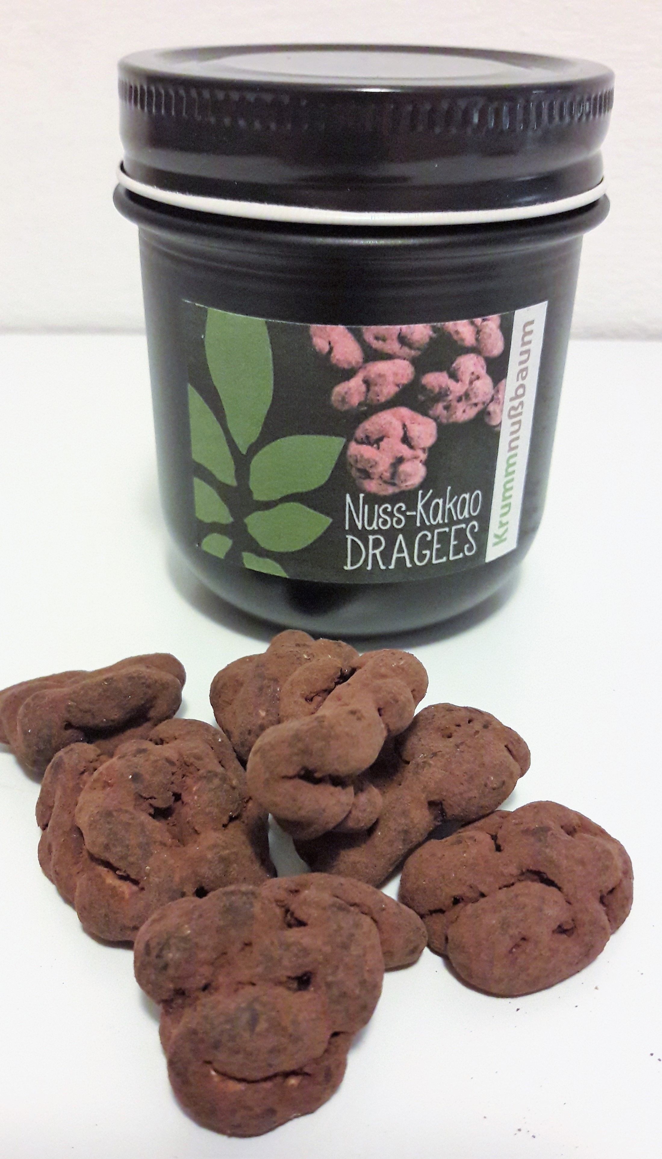 Nádoba s nápisom "Nuss-Kakao Dragees" a niekoľko dražé pred ňou.