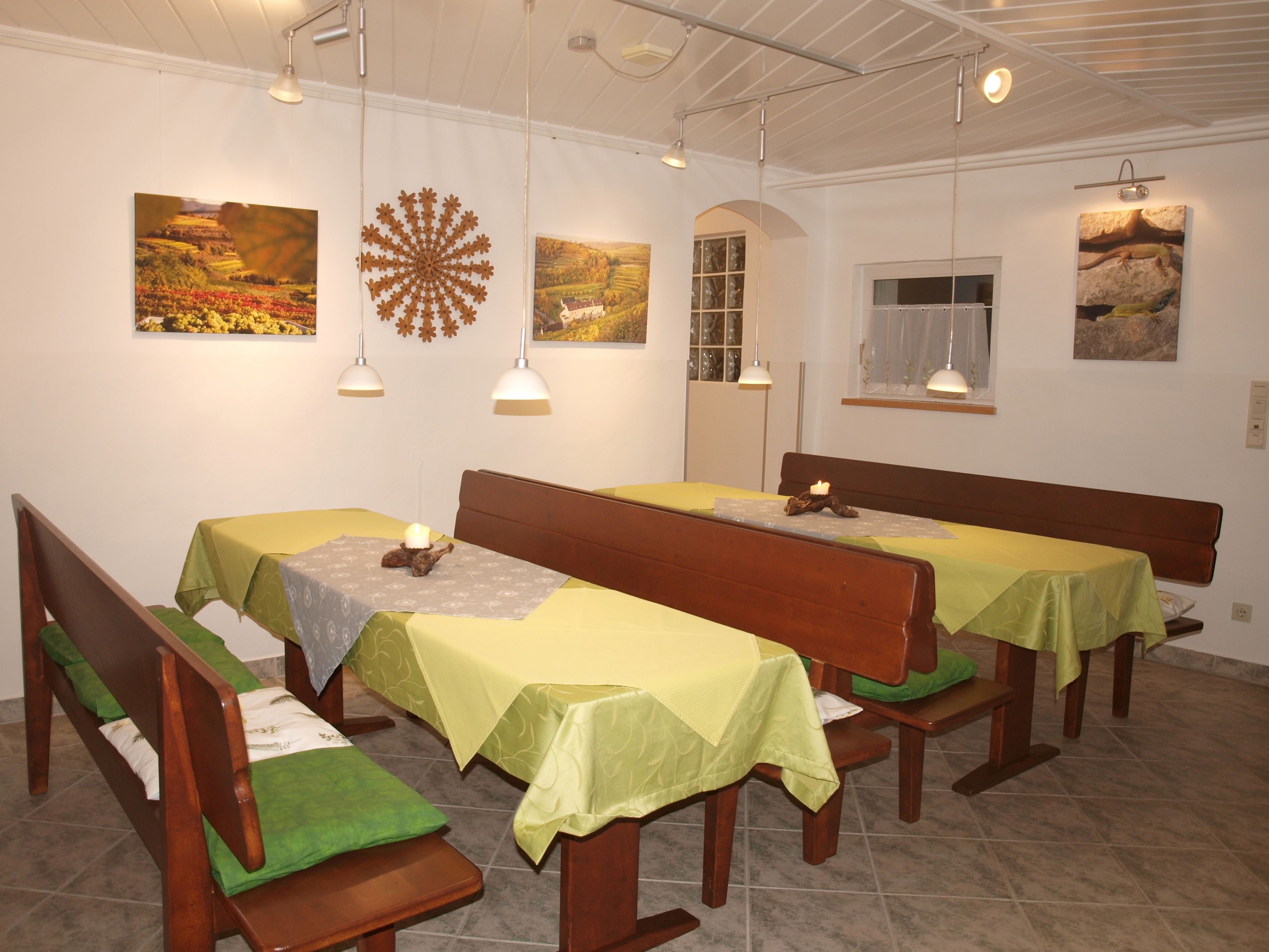 Útulná raňajková miestnosť s drevenými lavicami, zelenými obrusmi a nástennými dekoráciami.