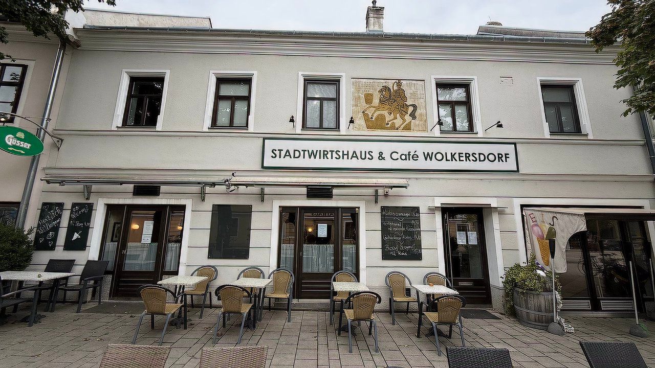 Exteriérový pohľad na Stadtwirtshaus & Café Wolkersdorf so stolmi a stoličkami na terase.
