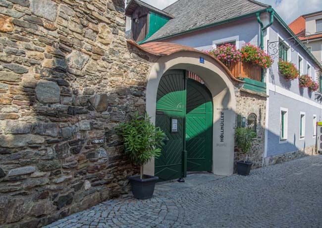 Historická budova so zelenou bránou a kvetmi.