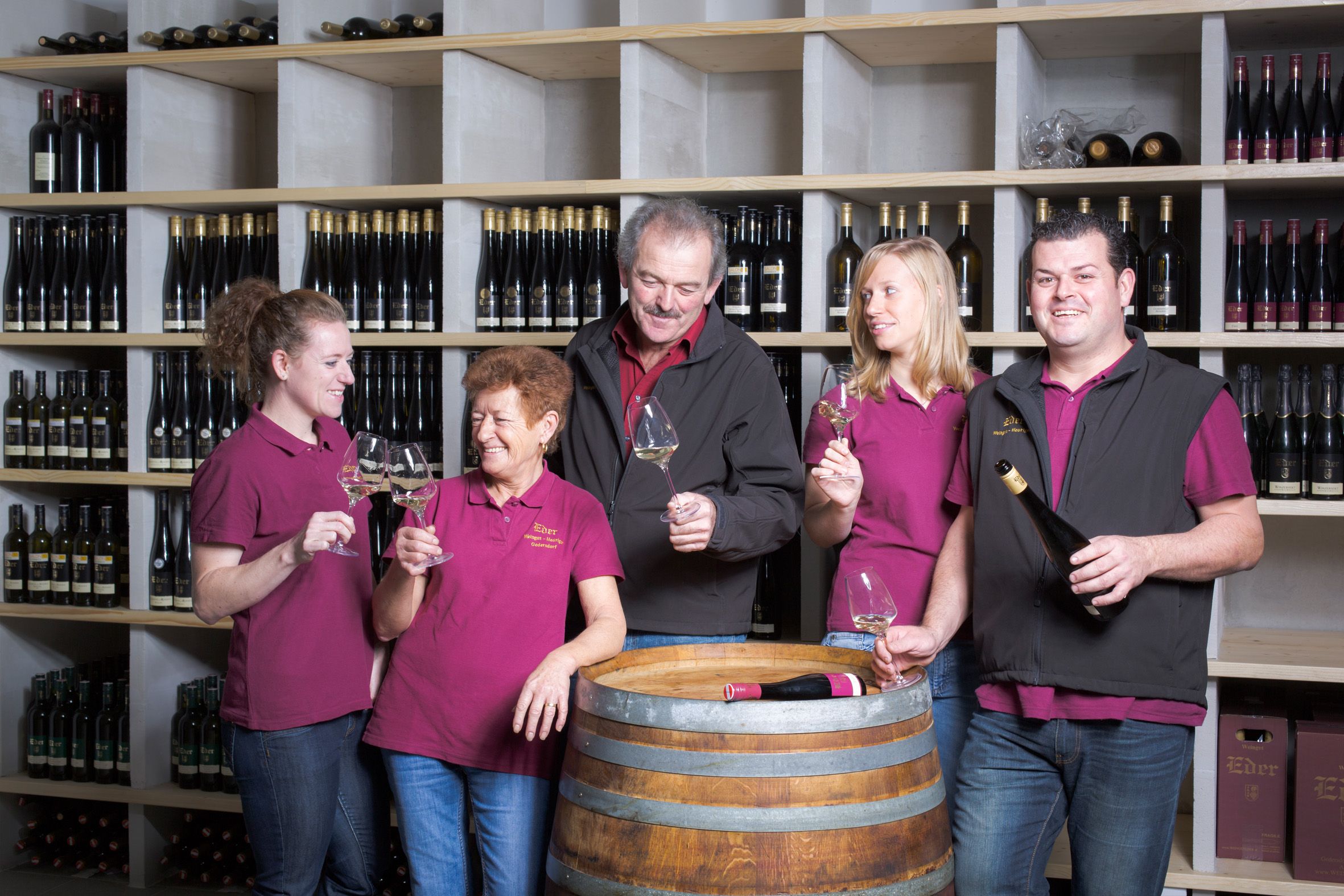 Päť ľudí vo vínnej pivnici si cinká pohármi.