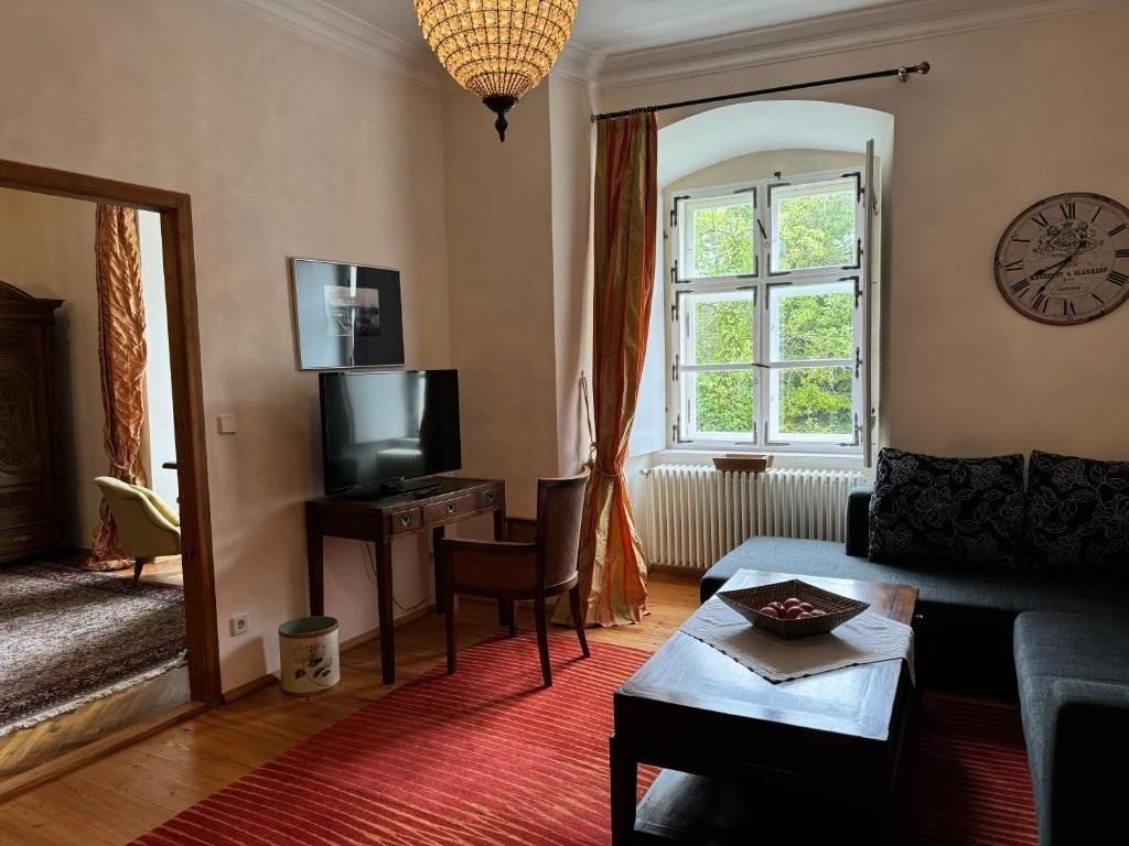 Útulná izba pre hostí s pohovkou, stolom, TV a veľkým oknom.