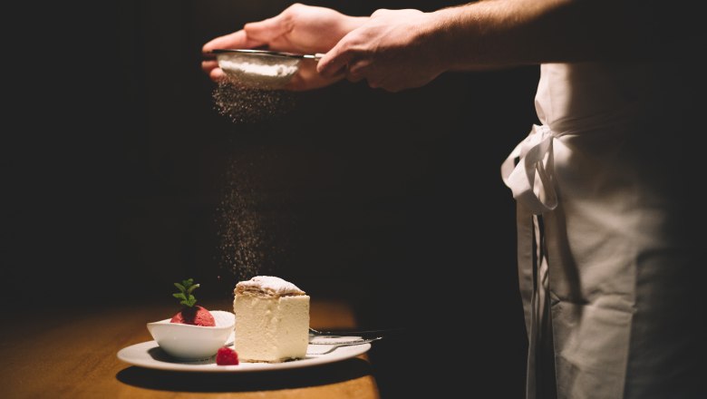 Tanier so šľahačkou a malinovým sorbetom, posypaný práškovým cukrom.