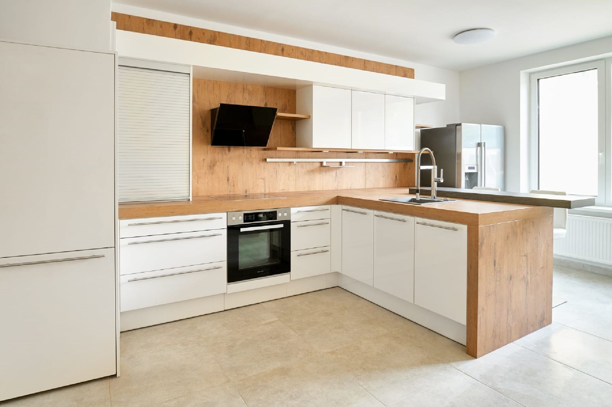 Moderná kuchyňa s drevenými a bielymi tónmi, sporákom, drezom a veľkým oknom.