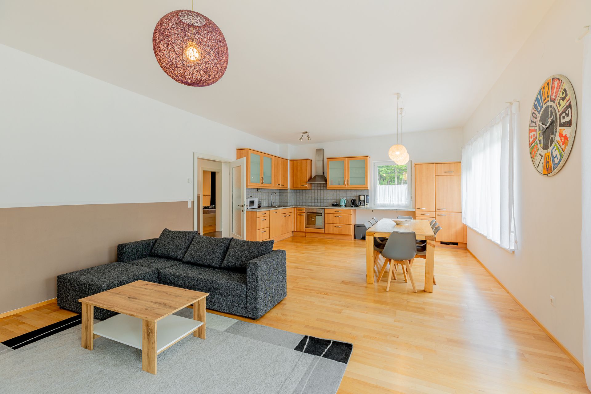 Otvorený obývací priestor s kuchyňou, jedálenským stolom a pohovkou.