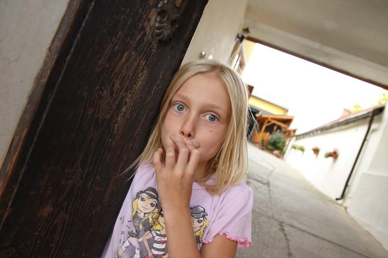 Dievča stojí v oblúku a prekvapene sa pozerá do kamery.