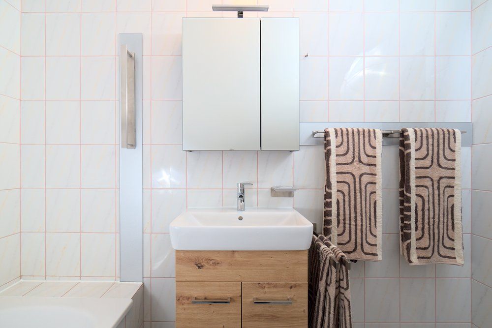 Moderná kúpeľňa s umývadlom, zrkadlom a uterákmi.