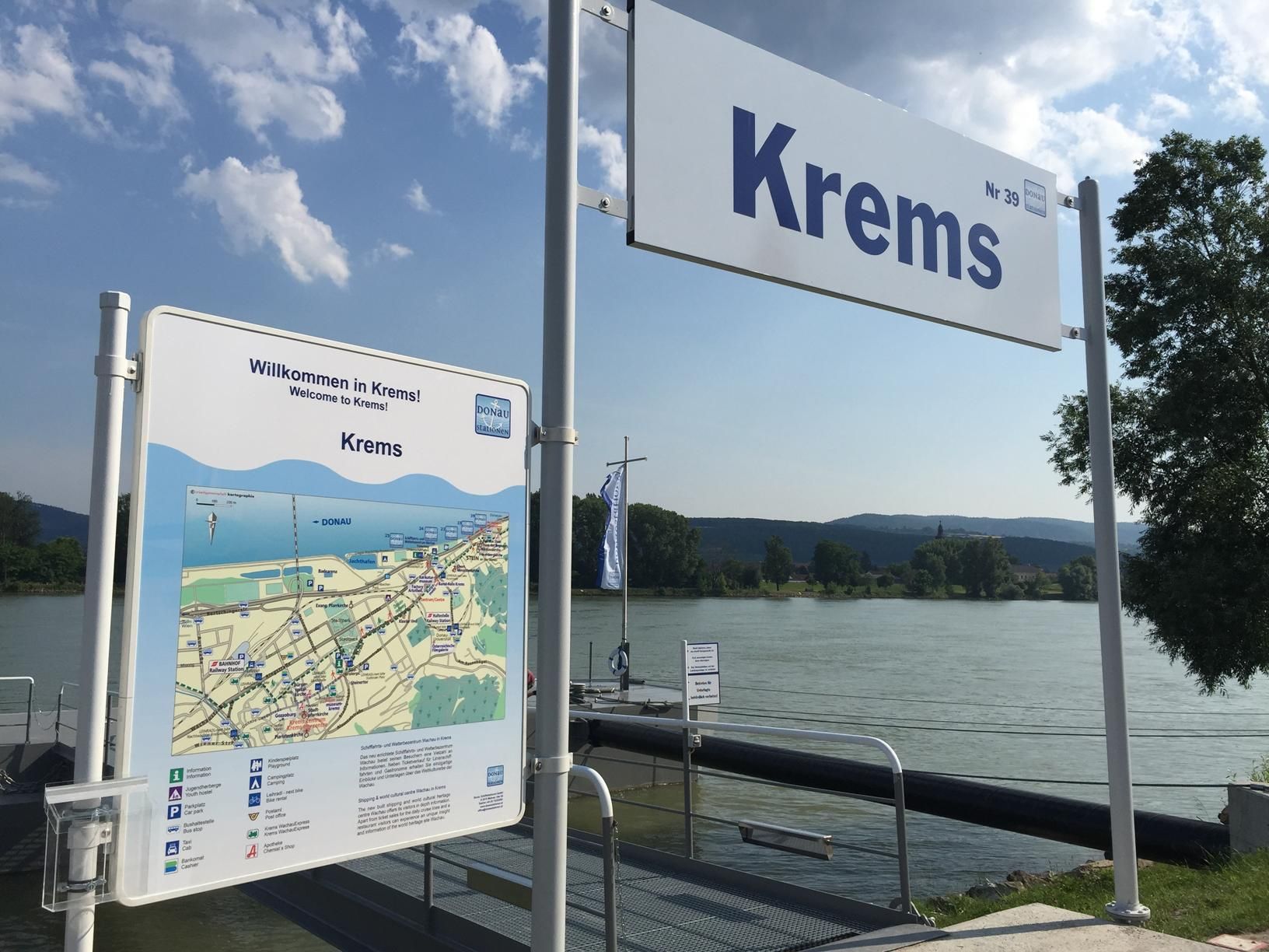 Prístavisko v Kremse s uvítacou tabuľou a Mapou, v pozadí rieka.
