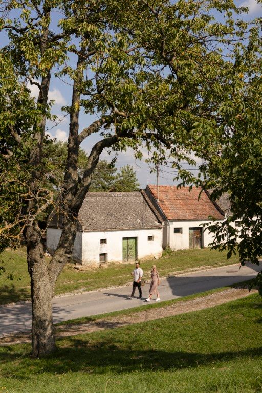 Dvaja ľudia prechádzajú okolo starých budov na vidieku.