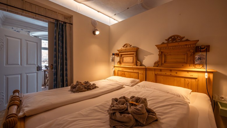 &Uacute;tuln&aacute; sp&aacute;lňa s dvoma samostatn&yacute;mi l&ocirc;žkami a dreven&yacute;mi dekor&aacute;ciami, pr&iacute;jemne osvetlen&aacute;.