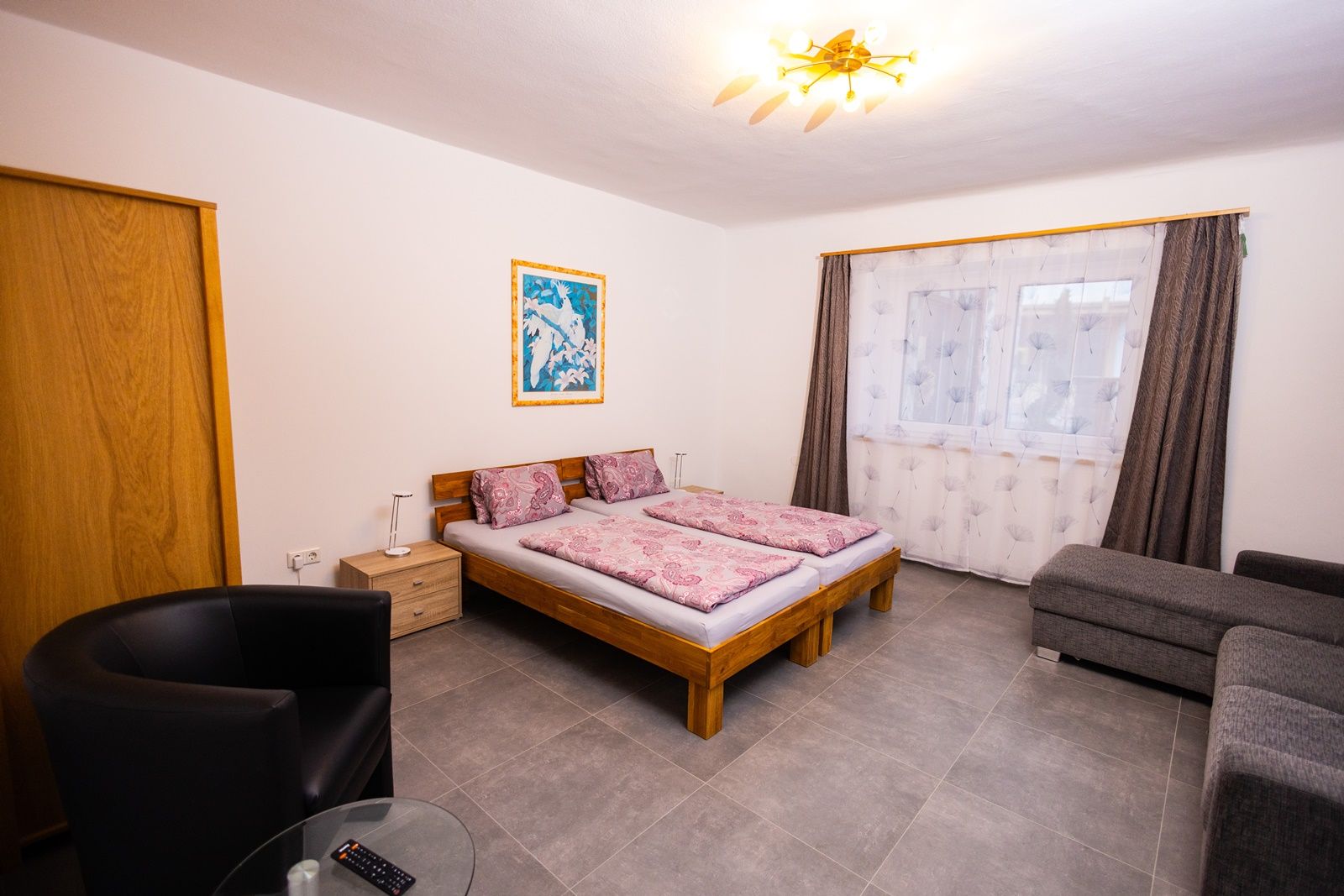 Spálňa s manželskou posteľou, pohovkou a kreslom.