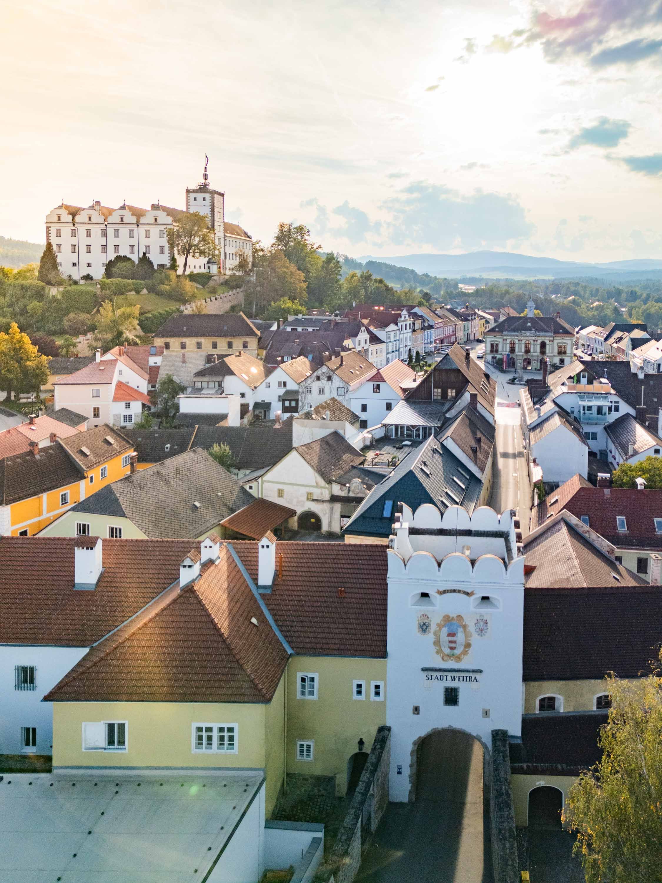 Letecký pohľad na historické centrum mesta Weitra s hradom a mestskou bránou v popredí.