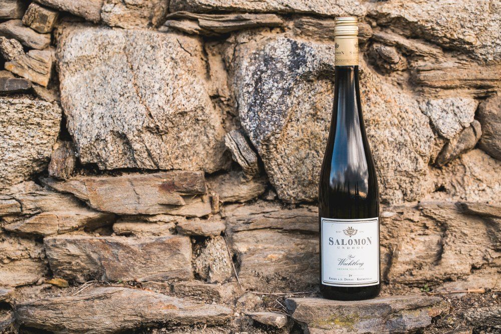 Fľaša vína pred kamennou stenou.