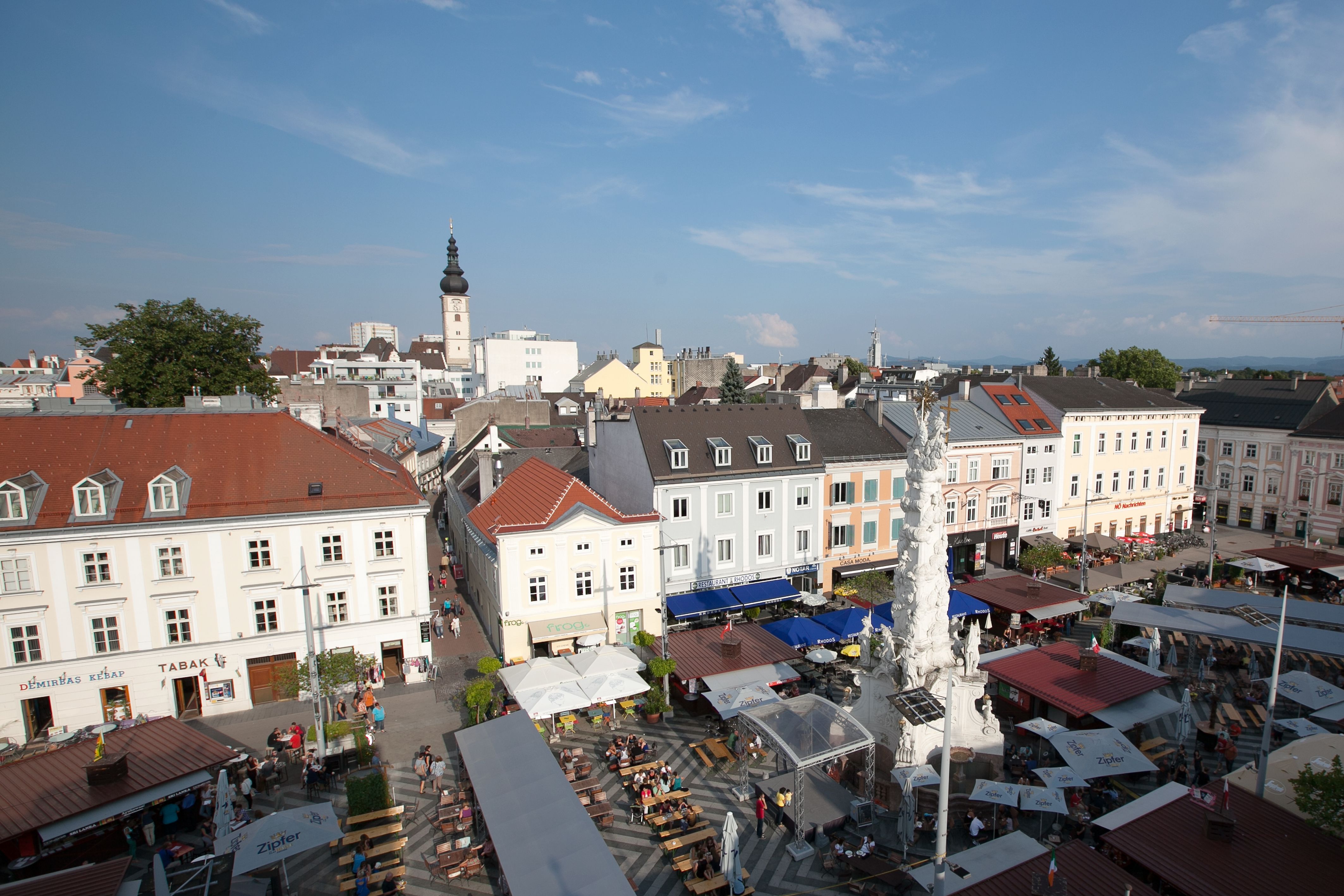 Letecký pohľad na rušné námestie v St. Pöltene so stánkami a vežou v pozadí.