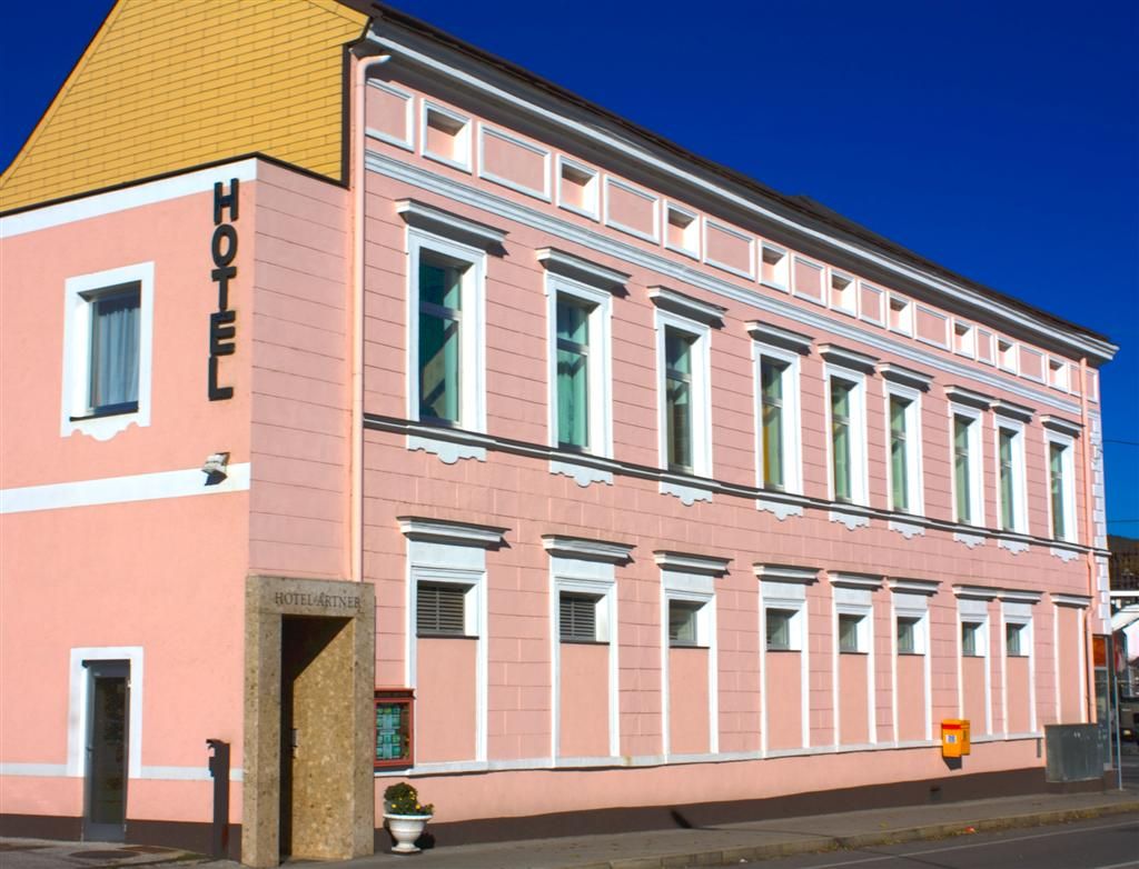 Ružová budova s nápisom "Hotel" na fasáde.