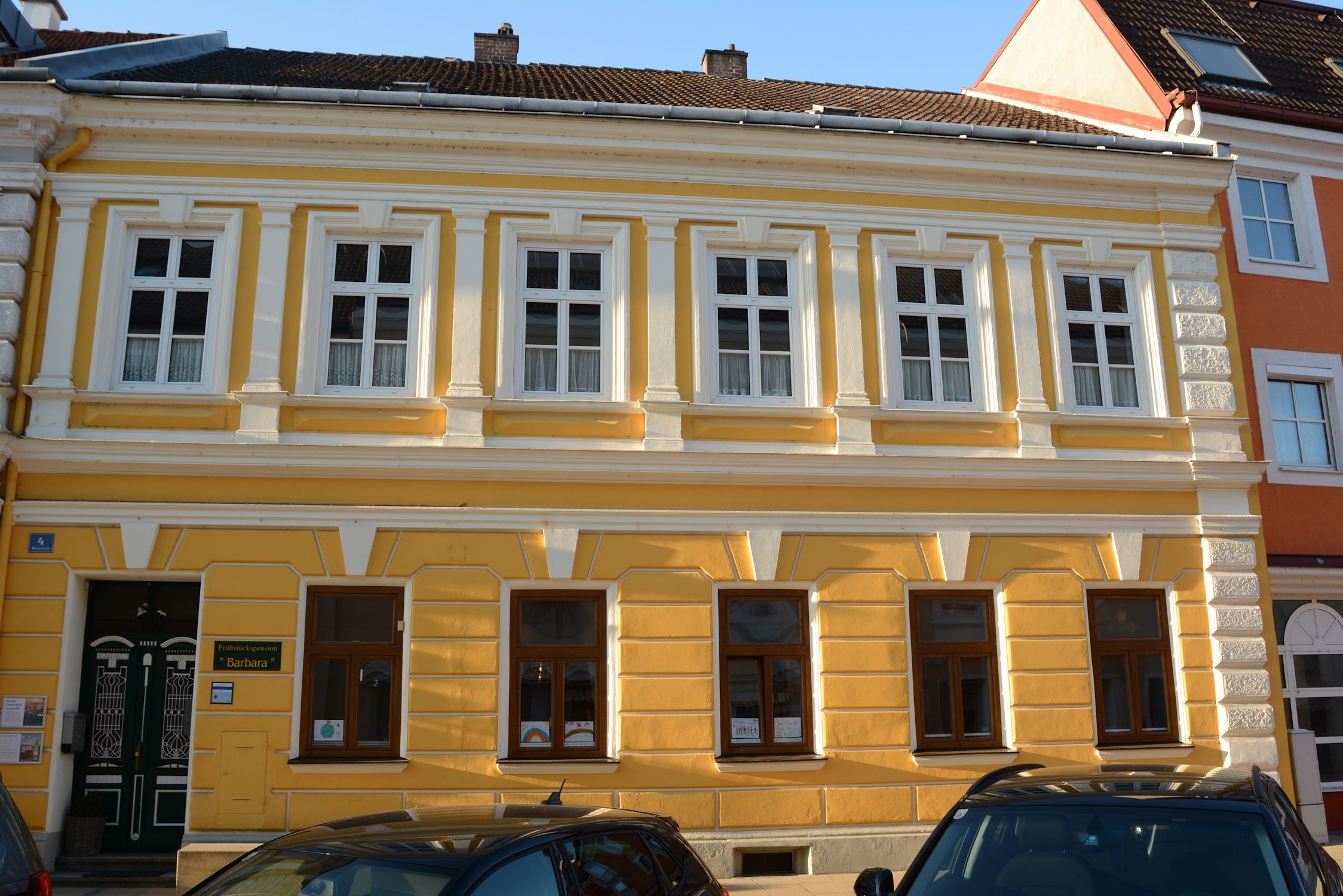 Žltá budova s bielymi okennými rámami a ozdobnými prvkami v Pöchlarne.