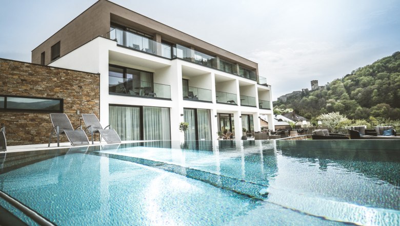 Boutique hotel "Das WeinSpitz", © © photography_pfeffel_at Moderný butikový hotel s bazénom a ležadlami, obklopený zelenou krajinou.