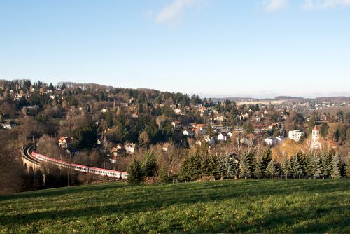 Krajina s vlakom na viadukte v Eichgrabene, obklopená kopcami a domami.