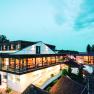 Moderná vinárska architektúra za súmraku s osvetlenými interiérmi a okolitými budovami.